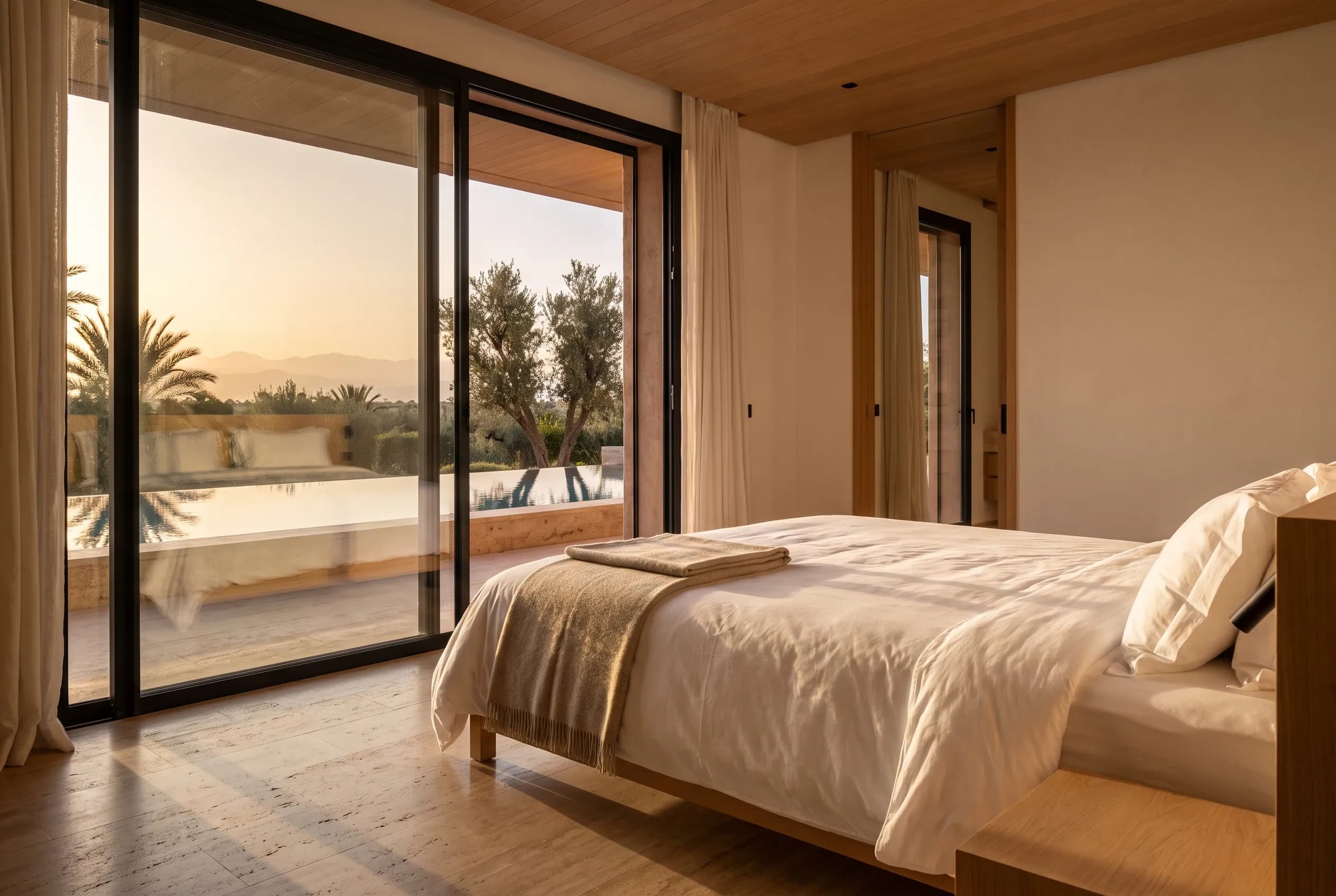 Master bedroom perfectly turned down, taut white linen catching low sun